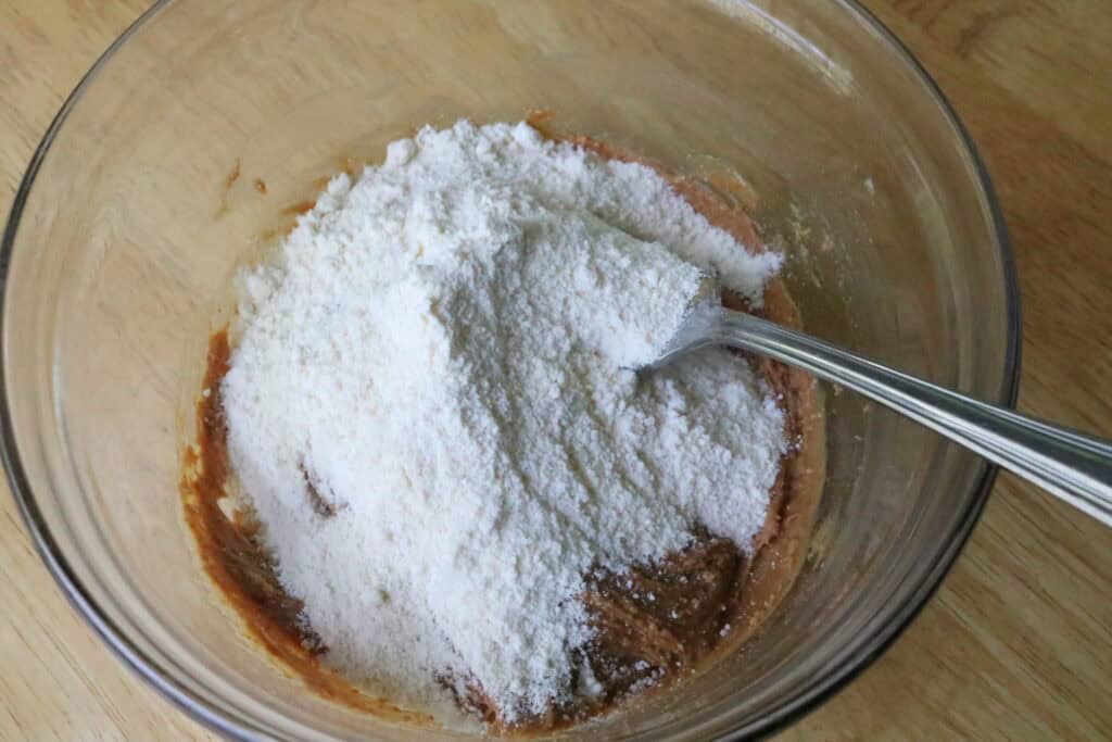 coconut flour on top of peanut butter in a glass bowl with a fork