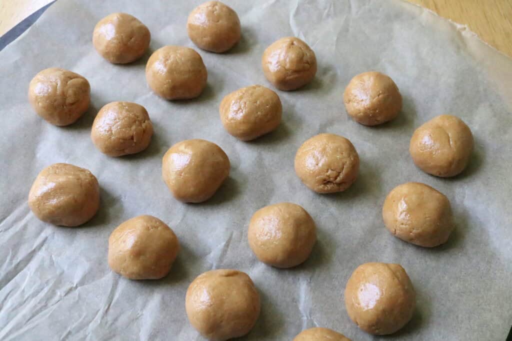 peanut butter balls on a parchment paper lined baking sheet