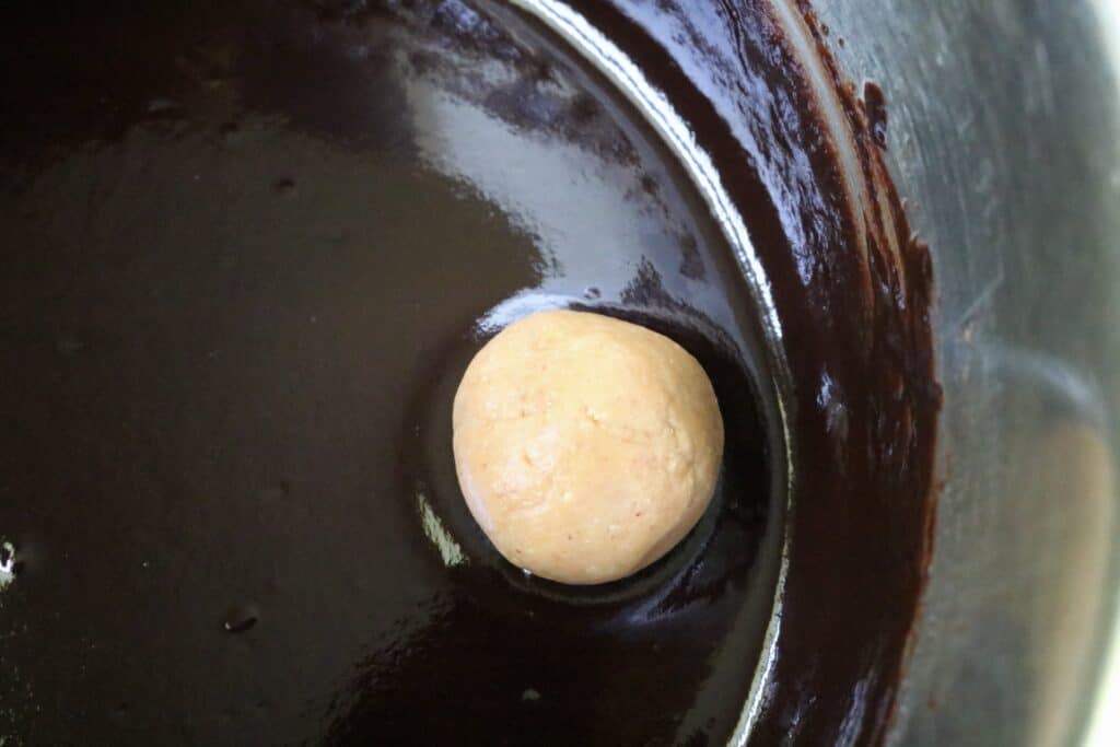 peanut butter ball in chocolate sauce in pan