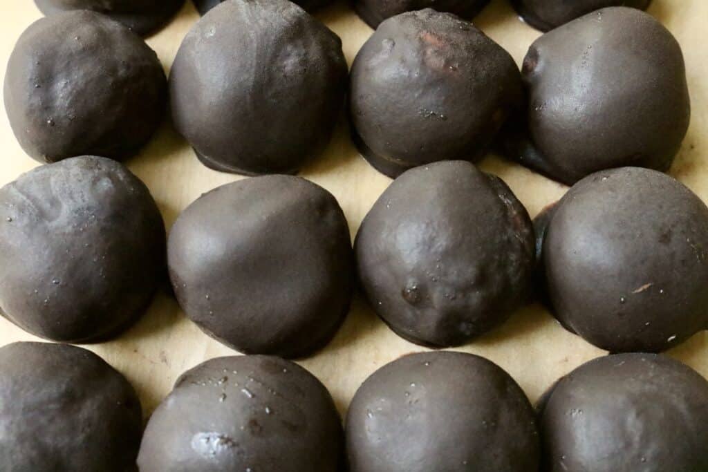 dark chocolate covered peanut butter balls lined up on counter top