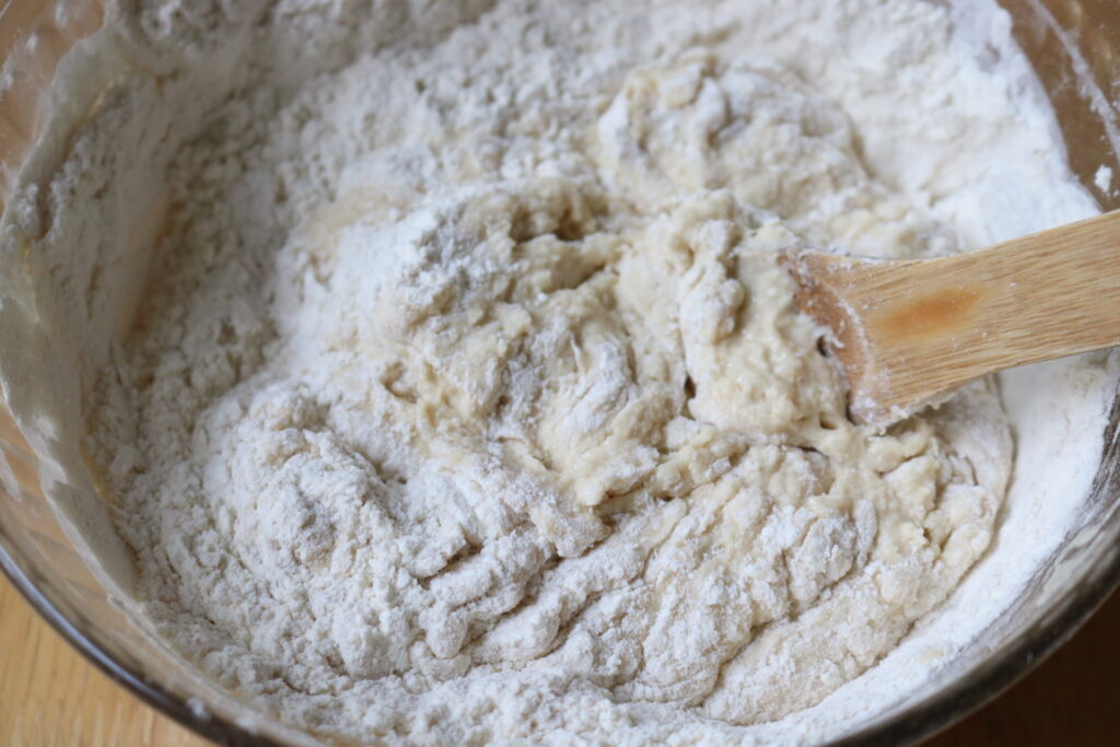 dough being stirred with a wooden spoon