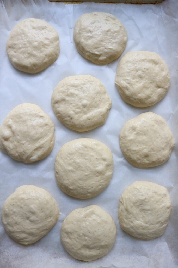 10 uncooked hamburger buns on a cookie sheet