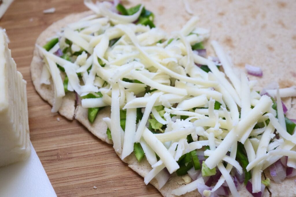 cut veggies and grated cheese on a tortilla