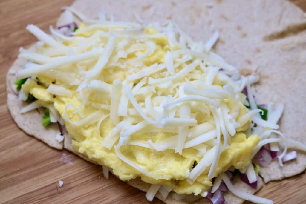 cooked egg and grated cheese on a tortilla