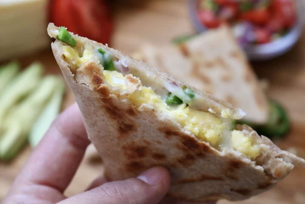 holding a quarter of a breakfast quesadilla