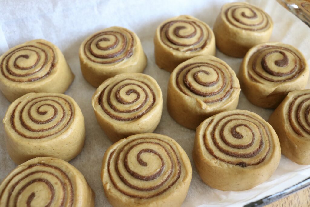 12 unbaked sourdough pumpkin cinnamon rolls on a baking sheet