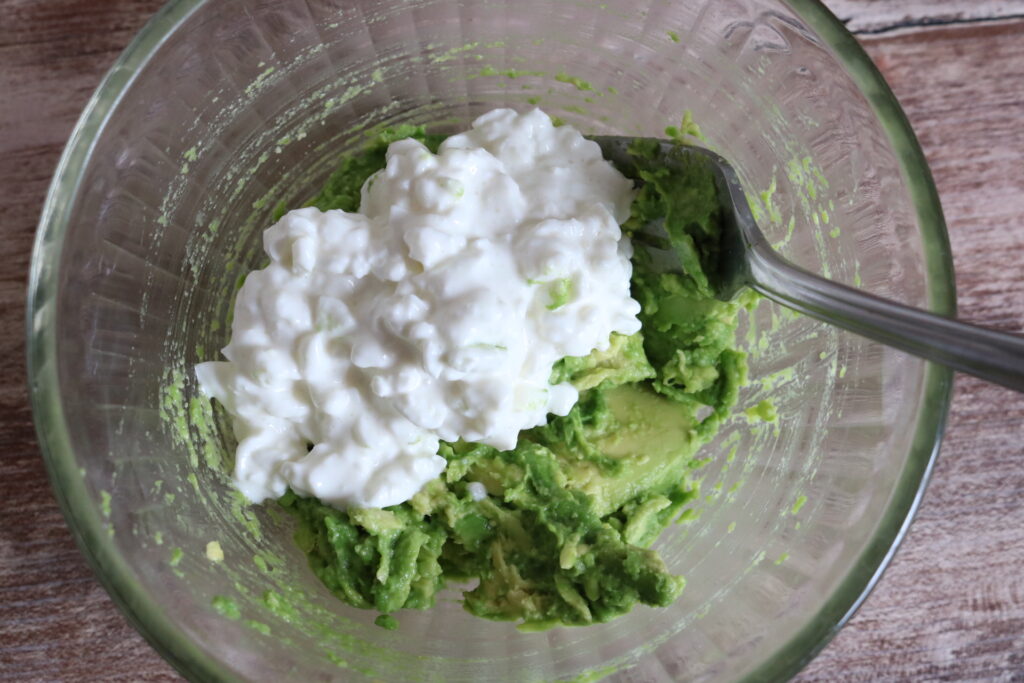 mashed avocado in a glass bowl with cottage cheese