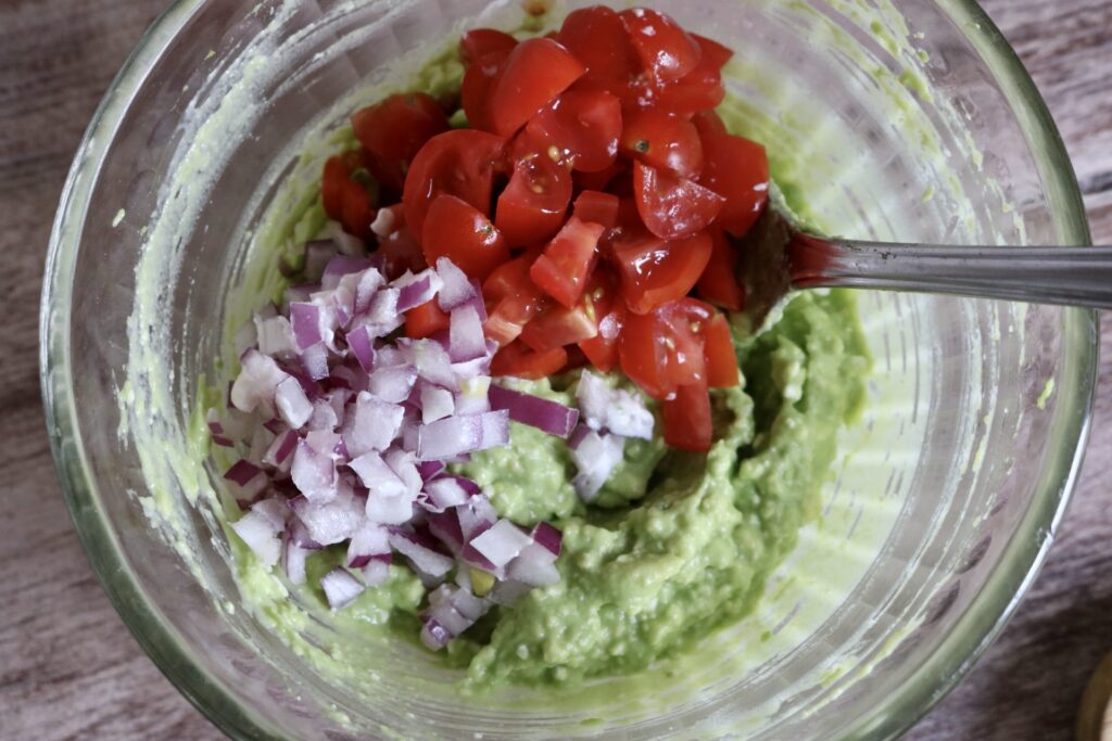 mashed avocado with chopped tomato and red onion on top
