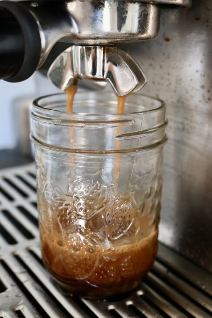 pulling a shot of espresso into a small glass jar