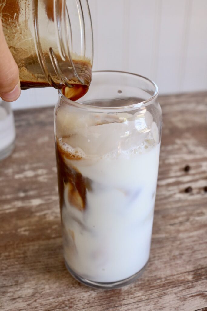 pouring coffee mixture over ice and milk