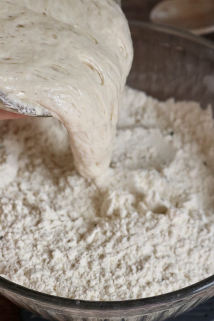 pouring sourdough starter into flour
