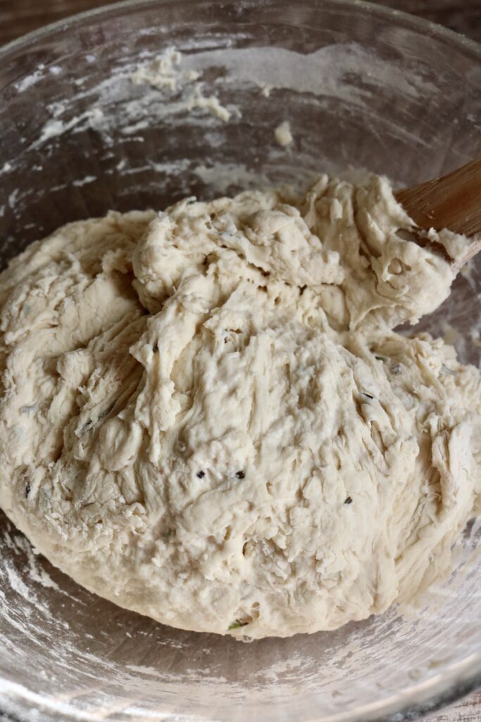 bread dough being mixed with a wooden spoon