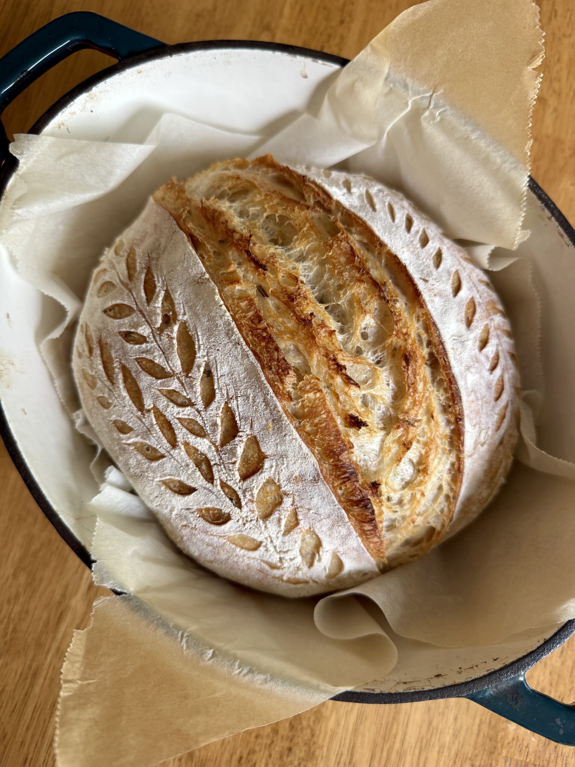 loaf of rosemary sourdough bread in a dutch oven