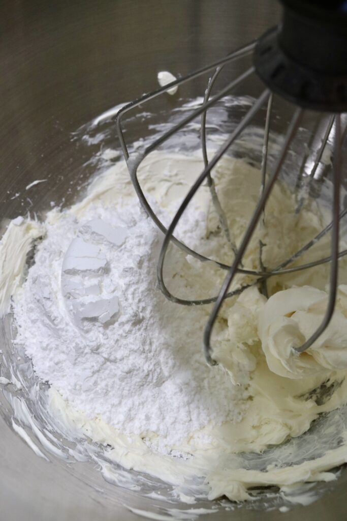 cream cheese and powdered sugar in the bowl of a stand mixer