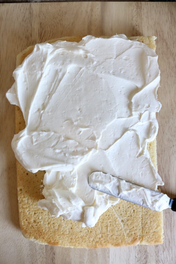 spreading a cake with whipped cream frosting with an icing spatula
