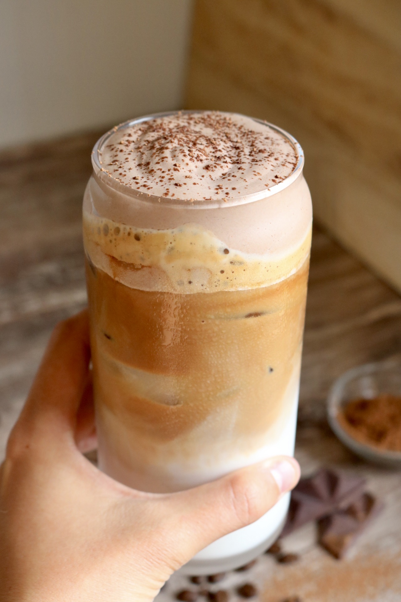 hand holding an iced latte with chocolate cold foam