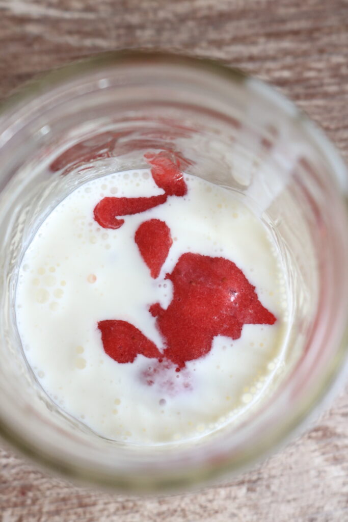 milk and strawberry puree in a small jar