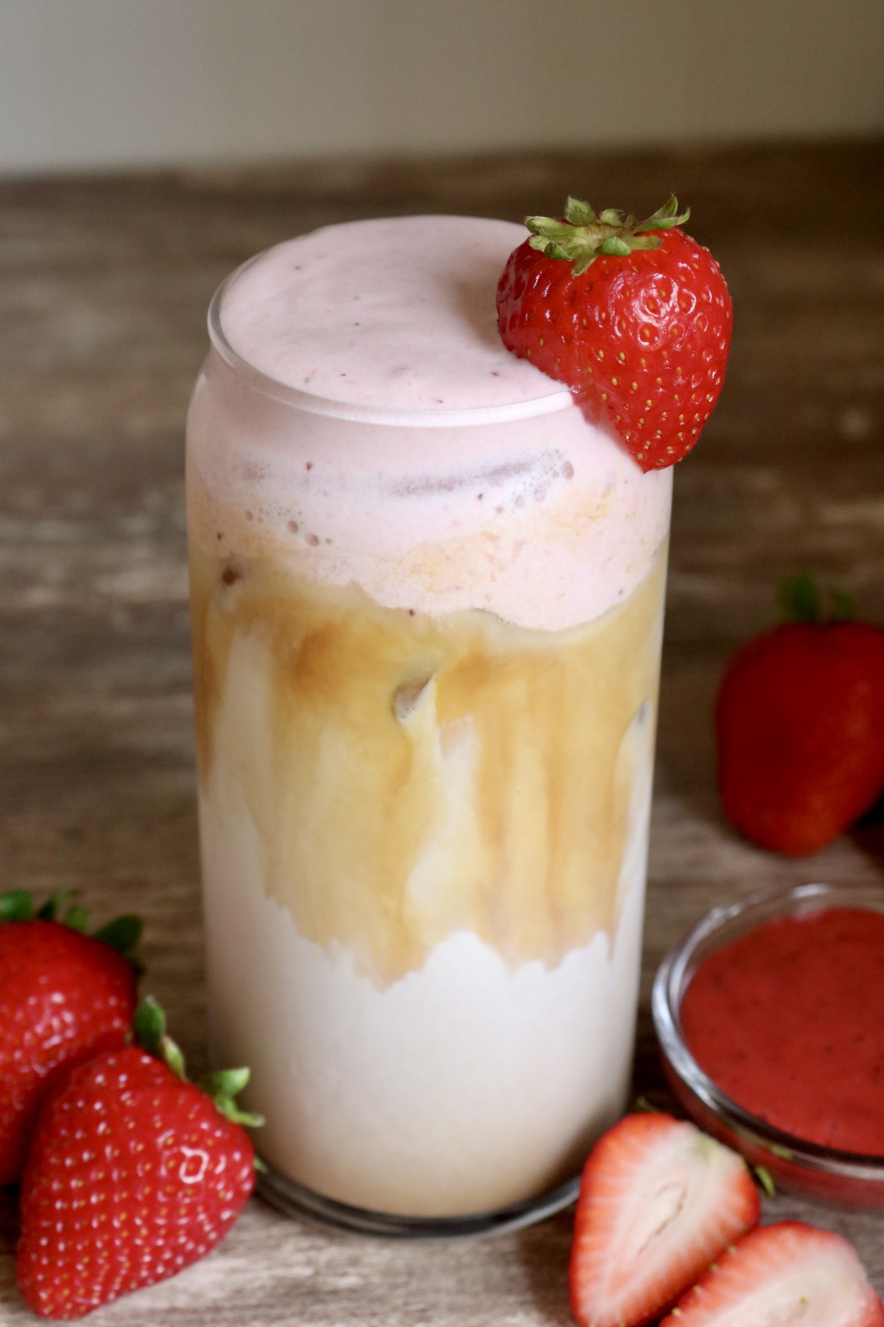 iced strawberry latte with whole fresh strawberry perched on the side of the glass