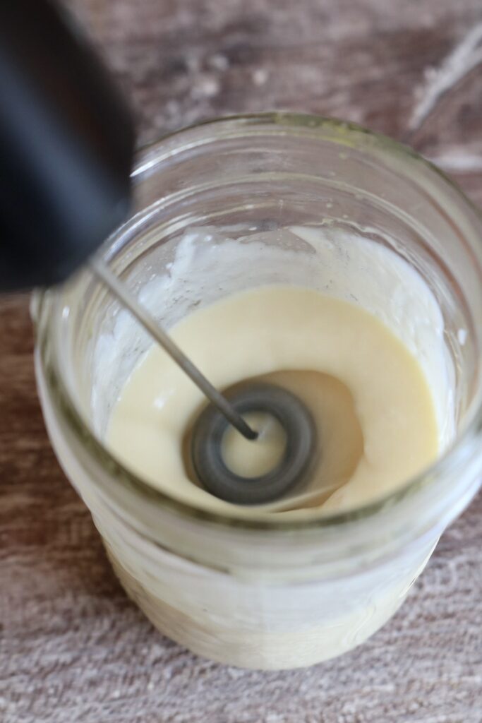 whipping orange cold foam with a handheld milk frother
