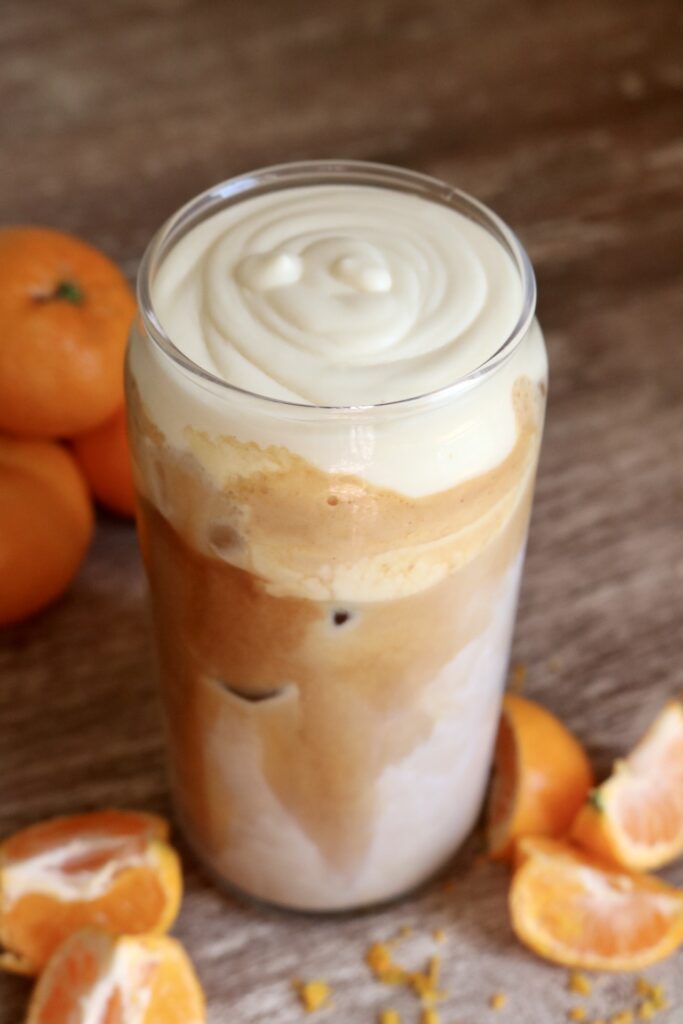 iced latte topped with orange cream cold foam
