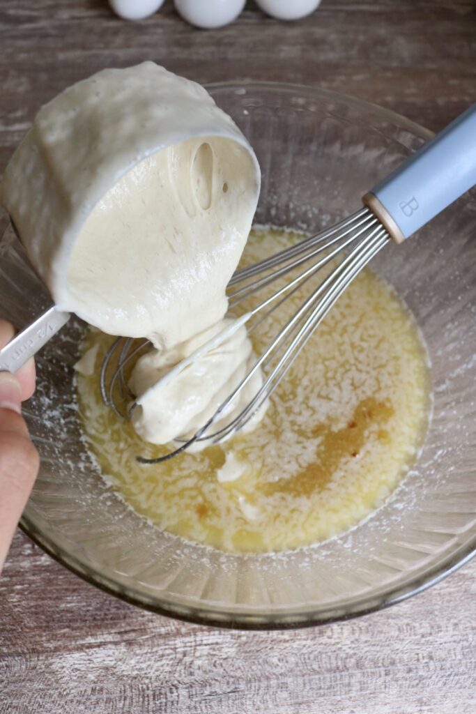 pouring sourdough starter into a bowl of melted butter