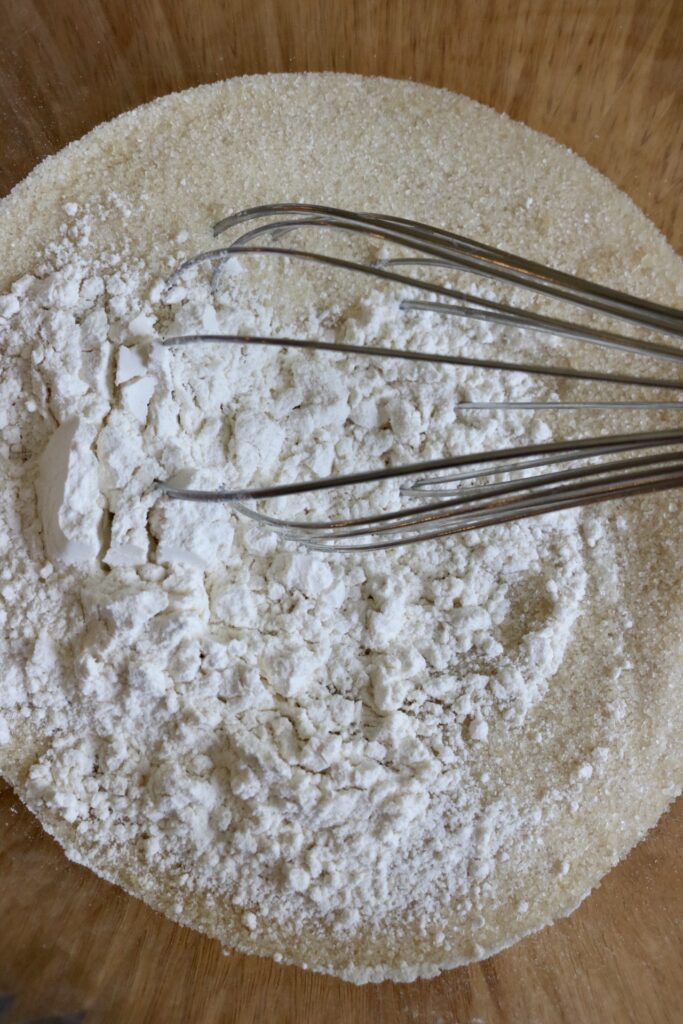 bowl of sugar and flour with a whisk in it
