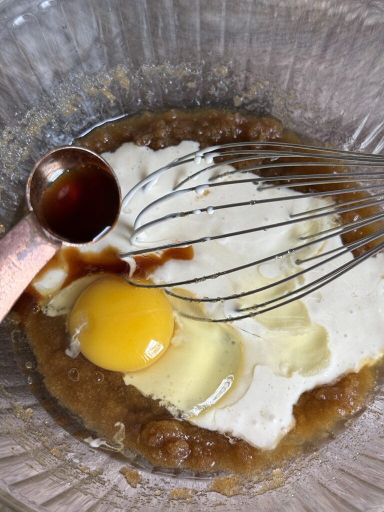 glass bowl with brown sugar and melted butter, egg, sourdough starter, pouring vanilla extract into the bowl