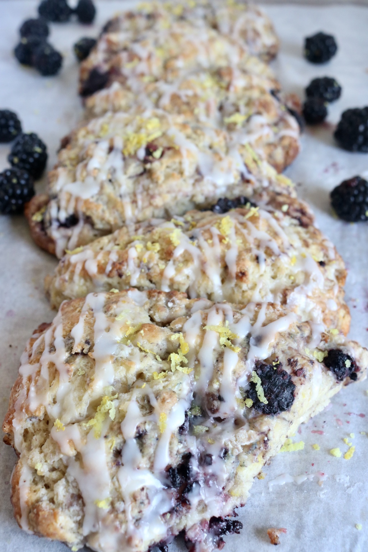 close up of a sourdough blackberry lemon sourdough scone with others lined up behind it