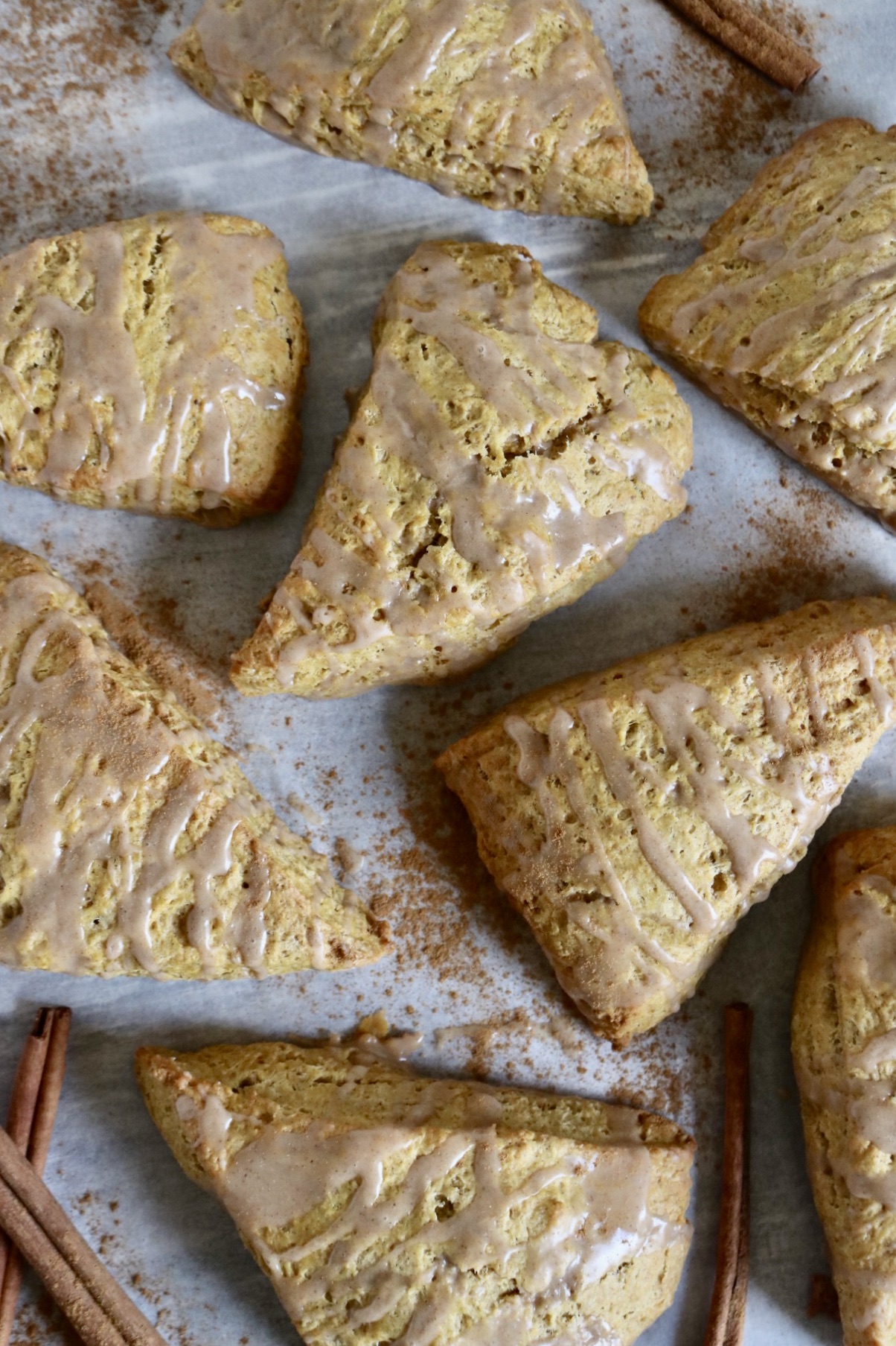 sourdough pumpkin scones set randomly on a white back round with cinnamon sprinkled here and there