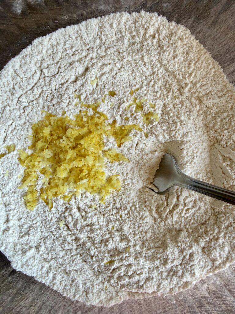 lemon zest in flour with a fork in a glass bowl