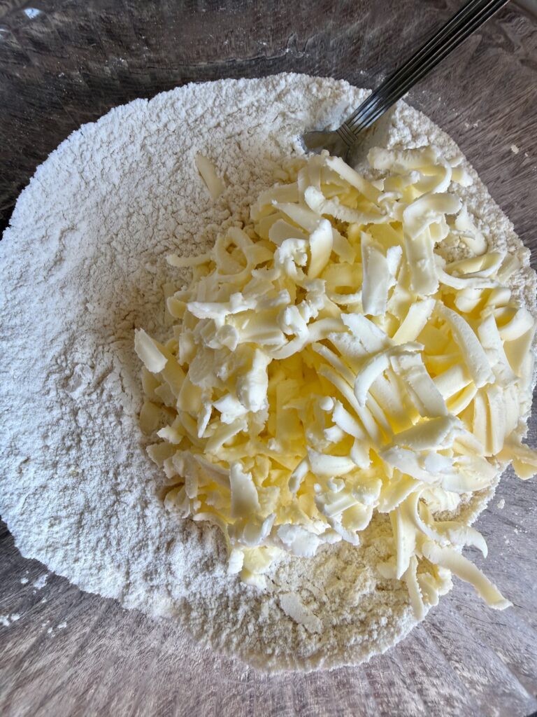 grated butter on top of flour in a bowl