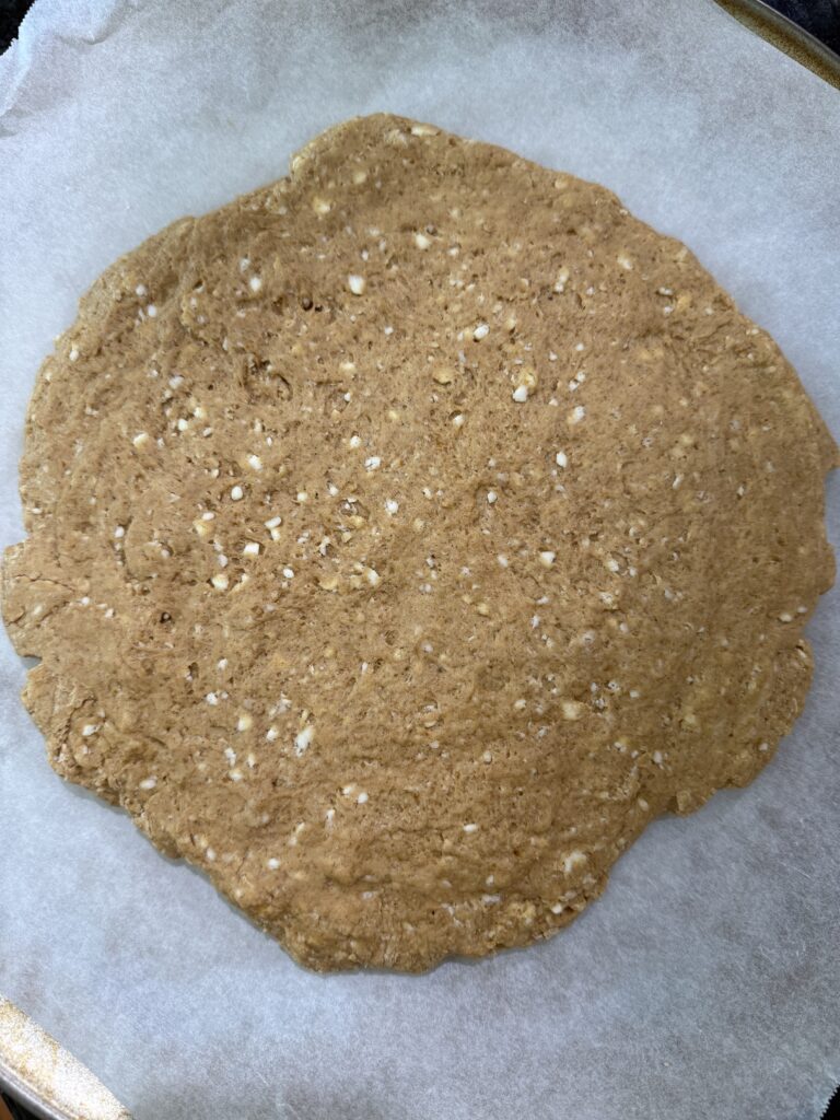 sourdough pumpkin scone dough pressed into a circle on a piece of parchment paper