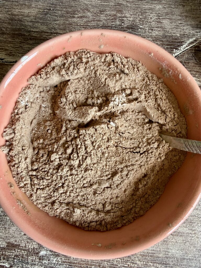mixing cocoa powder and flour in a pink bowl