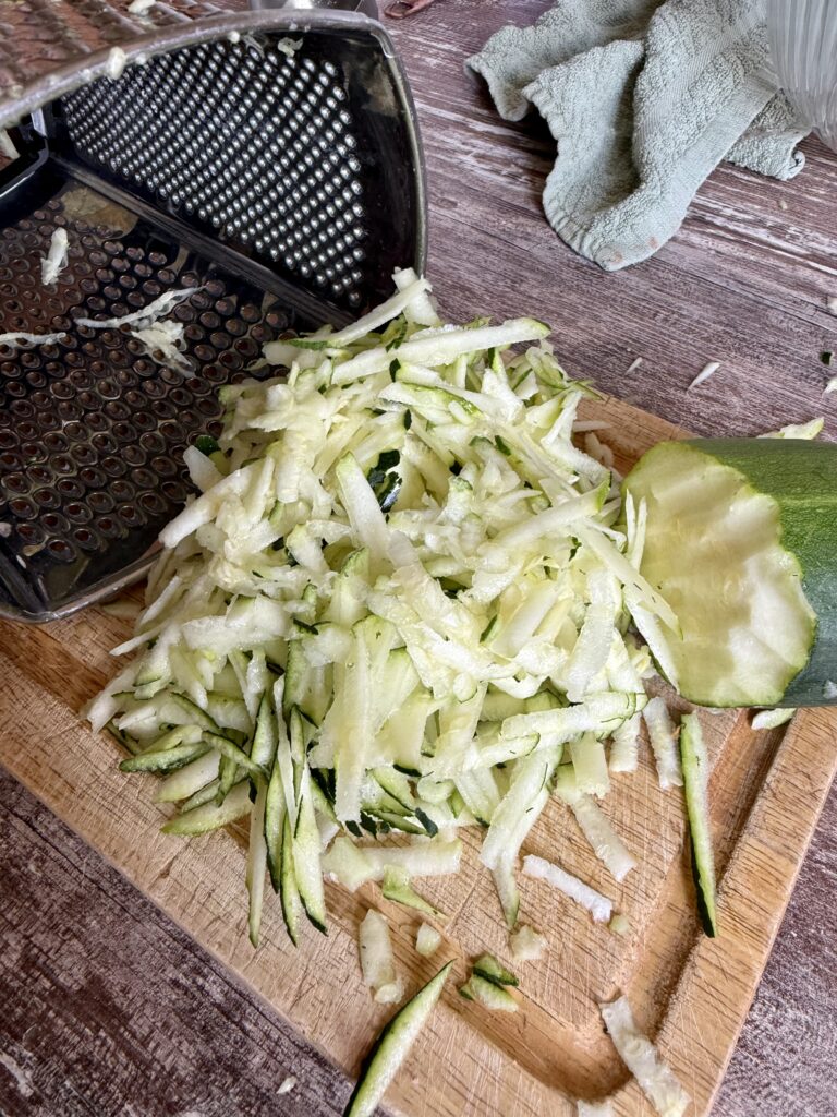 shredded zucchini on a wood cutting board