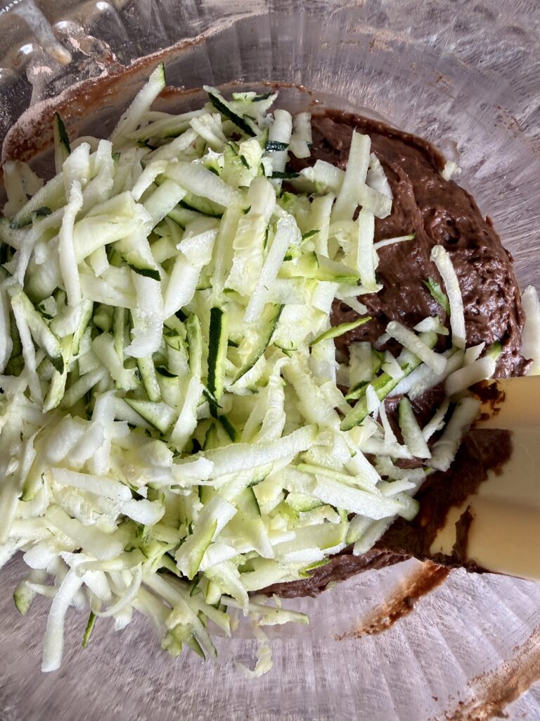shredded zucchini in a bowl of chocolate batter