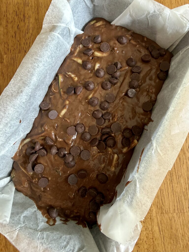 sourdough double chocolate zucchini bread batter in a loaf pan lined with parchment paper