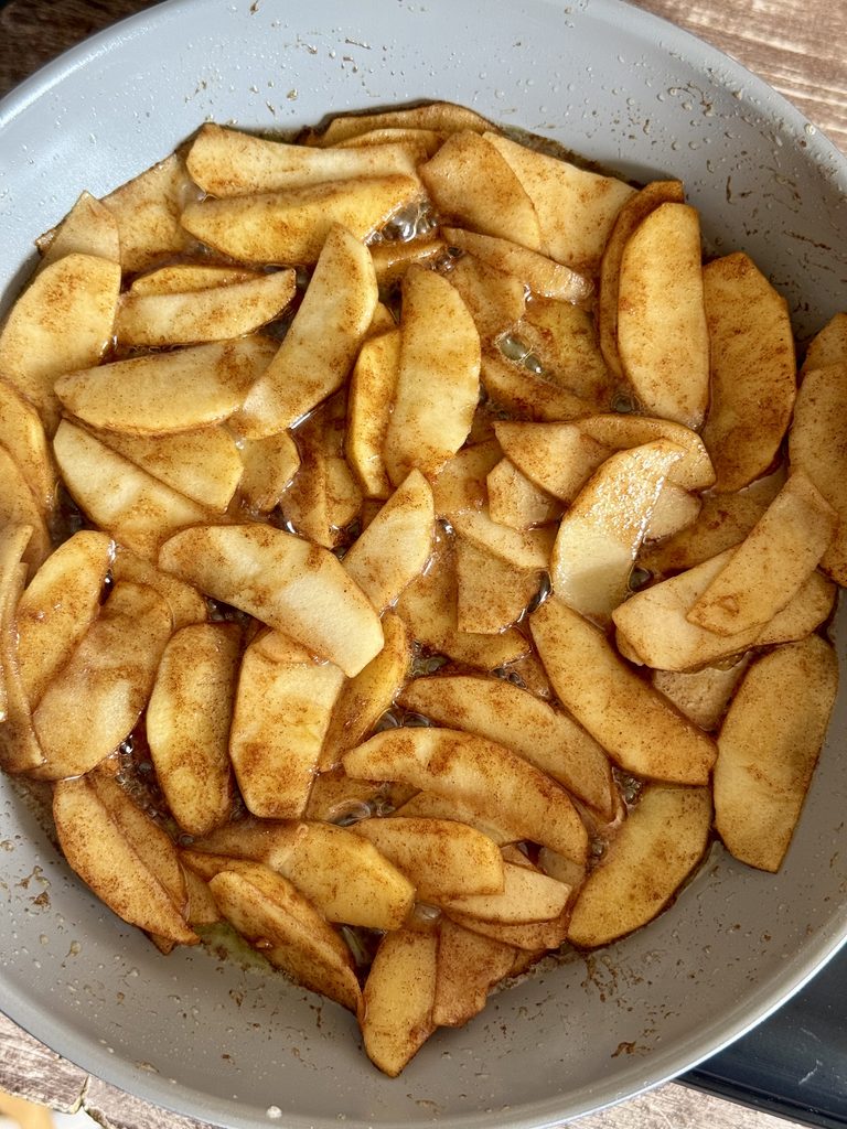 apples frying in a skillet with butter and cinnamon